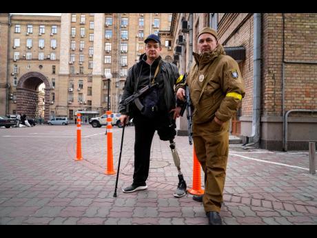 Armed civil defence men pose for a photo while patrolling an empty street due to a curfew in Kyiv. 