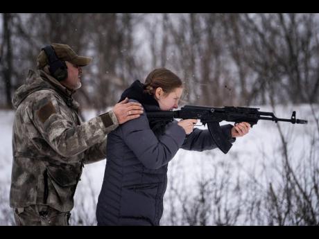 An instructor trains a woman to shoot from a Kalashnikov assault rifle at a shooting range near Kharkiv, Ukraine’s second-largest city