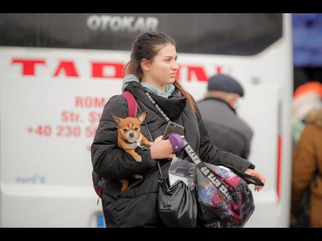 A refugee who fled the conflict from neighbouring Ukraine carries a dog at the Romanian-Ukrainian border in Siret, Romania.