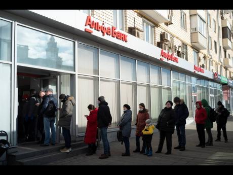 People stand in line to withdraw money from an ATM of Alfa Bank in Moscow.