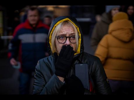 A woman reacts to sirens announcing new attacks outside a supermarket in central Kyiv, Ukraine, yesterday. 