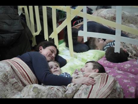 A woman and her children lie on the floor in the improvised bomb shelter in a sports centre, which can accommodate up to 2000 people, in Mariupol, Ukraine on Sunday.