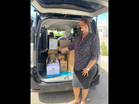 Credit: Contributed Shanique Sands, employee benefits officer at Caribbean Producers Limited displays some of the items donated to the Garland Hall Memorial Children’s Home as part of their partnership with The UWI Western Jamaica Campus Guild of students.