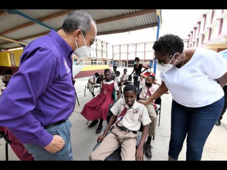 Dr Horace Chang, (left) minister of national security and Angela Brown Burke, MP for St. Andrew South Western chat with Jerdane Dixon, student of Greenwich Town Primary School during a tour yesterday of Greenwich Town where a zone of special operations (ZO