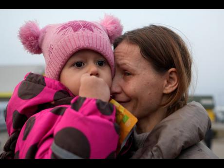 
A woman with a child who fled from the war in Ukraine reacts as they reuniting with their family after crossing the border in Medyka, Poland.