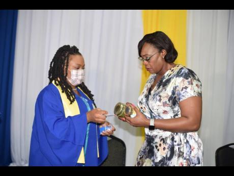 Credit: Contributed Owner of Wi Jammin Caribbean Foods, Sashell Thomas (left), shows her products to Deputy Speaker of the House and Guest Speaker Juliet Holness, shortly after the graduation service of the Northwest Manchester Youth Entrepreneurship programme at the Golf Vie