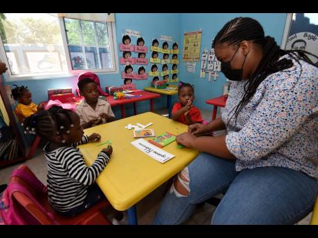 Asha Murray (right), from the Whitfield Town community, assists grade one students at Galilee Early Childhood Development Centre.