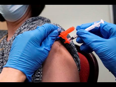 A woman receives a COVID-19 vaccine injection by a pharmacist at a clinic in Lawrence, Massachusetts in December 2021.