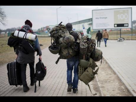A man carries combat gear as he leaves Poland to fight in Ukraine, at the border crossing in Medyka, Poland.