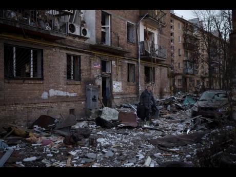 A resident carries a suitcase with his belongings after his building was heavily damaged by bombing in Kyiv, Ukraine yesterday.