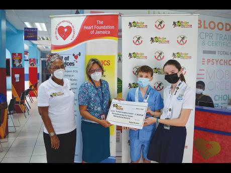 CONTRIBUTED
Students of Hillel High School, Abigail Corrigan (right) and Cormac Corrigan (second right), hand over a symbolic cheque for $164,876 to Deborah Chen (second left), executive director of the Heart Foundation of Jamaica, while Diane Ellis, direc