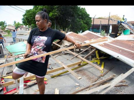 A vendor assists in the dismantling of stalls located at the southwestern end of National Heroes Circle on Sunday. A traditional spot for the sale of crab, corn, and soup, the vendors will be temporarily located. New stalls are reportedly under constructio