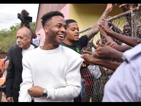 Manchester City forward Raheem Sterling (left) and Aston Villa winger Leon Bailey are thronged by fans at the Trench Town football field during the visit of the Duke and Duchess of Cambridge on Tuesday. Sterling, who was born in Jamaica, has been appointed