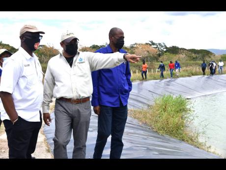 Peter Clarke (centre), managing director of the Water Resources Authority, indicates a matter of interest to Minister of Local Government and Rural Development Desmond McKenzie (left) and Josephs Gyles, CEO of the National Irrigation Commission, during a t