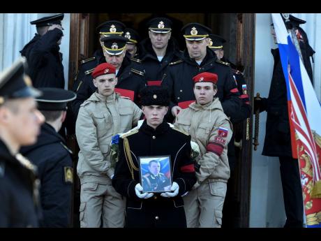 A serviceman carries the photo of Captain Andrei Paliy, a deputy commander of Russia’s Black Sea Fleet, during a farewell ceremony in Sevastopol, Crimea, yesterday. Paliy was killed in action during fighting with Ukrainian forces in the Sea of Azov port 