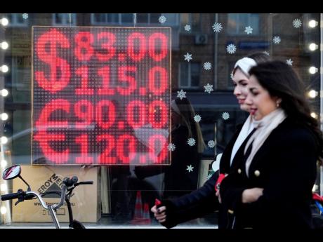 AP 
People walk past a currency exchange office screen displaying the exchange rates of U.S. dollar and euro to Russian rubles in Moscow’s downtown, Russia, on February 28, 2022. 