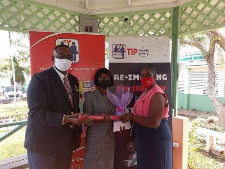 Credit: Contributed Dr Garth Anderson (left), president of the TIP Friendly Society and Cecelia Grant Francis (right), board member, TIP Friendly Society, Manchester hands over gifts to retired TIP member Marilyn Mason-Anderson.
