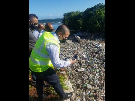 Credit: Paul H Williams Minister without Portfolio in the Ministry of Growth and Job Creation, Senator Matthew Samuda, taking pictures of the massive pile-up of plastic bottles at the mouth of the Franklyn Town Gully beside the Rae Town Fishing Village in Kingston.