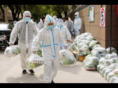 Volunteers carry daily necessities for residents in Fengxian District in eastern China’s Shanghai city on Monday. China began its most extensive coronavirus lockdown in two years Monday to conduct mass testing and control a growing outbreak as questions 