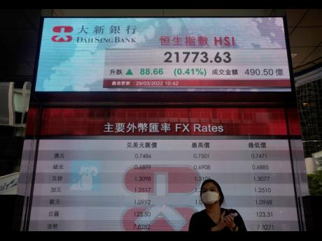 Credit: AP A woman walks past a bank’s electronic board showing the Hong Kong share index in Hong Kong Tuesday, March, 29, 2022.