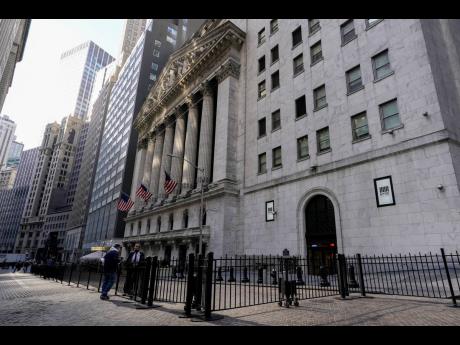 A trader (right) talks to a pedestrian outside the New York Stock Exchange on January 14, 2022, in the New York Financial District. 