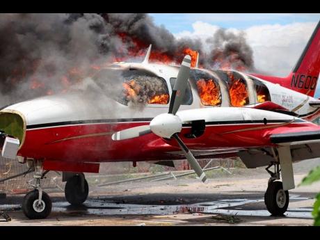 A plane burns after being set on fire by demonstrators protesting increasing violence at the Antoine Simon Des Cayes airport in Les Cayes, Haiti, yesterday. 