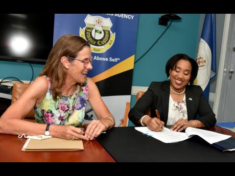 Judith Slater (left), British High commissioner to Jamaica, looks on as Velma Ricketts Walker, commissioner of customs, signs a memorandum of understanding, in Kingston on Tuesday. The pact seeks to boost Jamaica’s border-protection capacity.