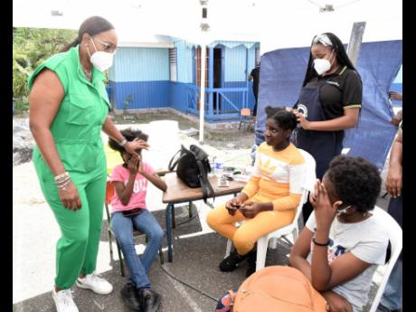 Credit: Ian Allen Juliet Holness (left), member of parliament, St Andrew East Rural, speaks with girls who attended the Indian High Commission Medical Camp at the St Martin de Porres Primary School in Gordon town on Sunday.