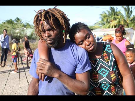 Owen Tomlinsonson of Haylesfield, Clarendon, supports his partner Micey Walters after she returned from hospital following the death of her two children.