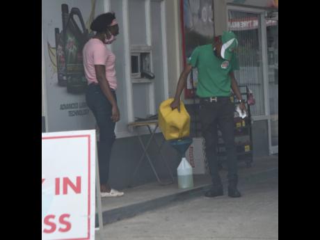 An attendant pours petrol from a gas jug into a gallon bottle as an undercover Sunday Gleaner reporter makes a $500 purchase in Rockfort, Kingston. The attendant said that the management of the station told him this was the safe way to fulfil such orders.