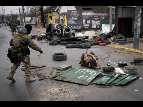 Ukrainian servicemen check streets for booby traps in the formerly Russian-occupied Kyiv suburb of Bucha, Ukraine, Saturday, April 2. As Russian forces pull back from Ukraine's capital region, retreating troops are creating a "catastrophic" situation for c