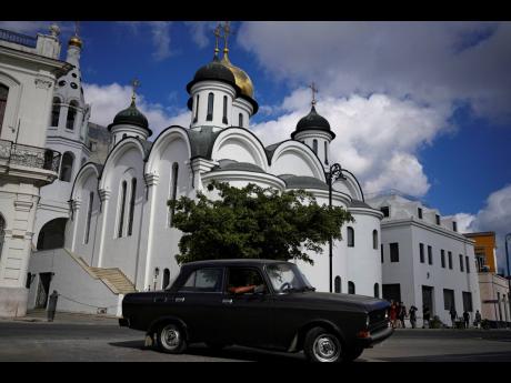 A vintage Russian-made Lada car passes the Russian Our Lady of Kazan Orthodox Cathedral in Havana, Cuba, Friday, April 1. Global restrictions on transport and trade with Russia after its invasion of Ukraine pose a serious problem for Cubans because much of