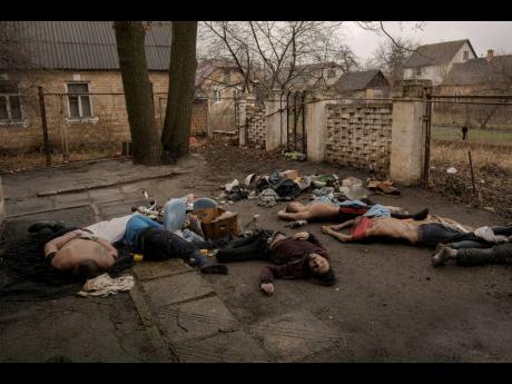 Lifeless bodies of men, some with their hands tied behind their backs, lie on the ground in Bucha, Ukraine, yesterday. 