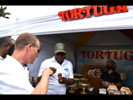 Adam Stewart (left), executive chairman of Sandals Resorts International and  Edmund Bartlett, Minister of Tourism, sample the Tortuga Rum Cakes during the Blue Mountain Coffe Festival at Devon House on Saturday.