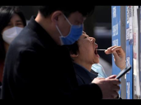 Residents line up to get their throat swab at a coronavirus testing site in Beijing yesterday. 