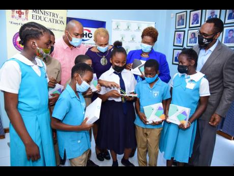 Minister of Education and Youth, Fayval Williams (background, second left), points out something on a tablet being held by Amoya Perry from Randolph Lopez School of Hope, during a ceremony for the handover of devices to four Corporate Area schools, the off