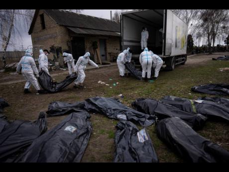 Volunteers load bodies of civilians killed in Bucha on to a truck to be taken to a morgue for investigation, in the outskirts of Kyiv, Ukraine, on Tuesday. 