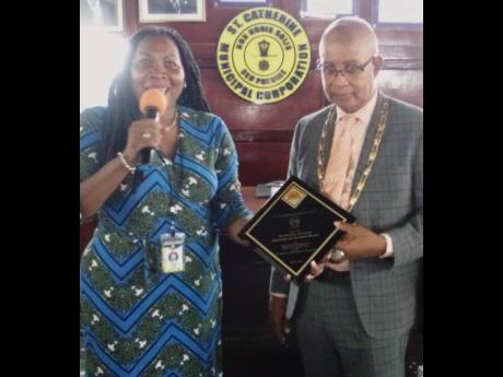 Councillor Pat Harris presents Spanish Town Mayor Norman Scott with plaque in recognition of the milestone.