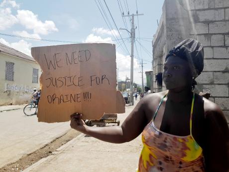 Credit: Photo by David Salmon A demonstrator protests the killing of 32-year-old Horaine Glenn in Denham Town, Kingston.