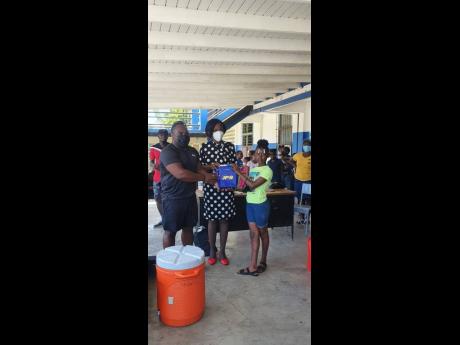 Bertram Anderson, student services and development Manager of the Elsa Leo Rhynie Hall, UWI, and principal of Morant Bay Primary, Faye Lindsay hand over a tablet sponsored by the JPS Foundation to Landrea Whyte who was one of the top three students in an e