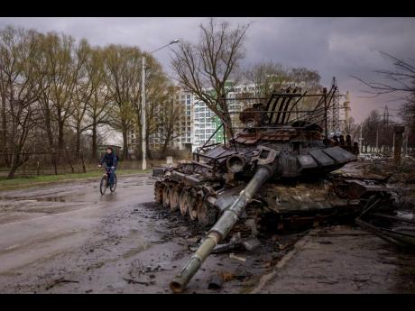 A man rides his bicycle next to a destroyed Russian tank in Chernihiv, Ukraine, yesterday.