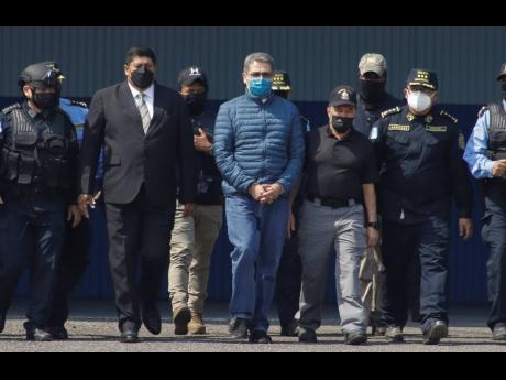 Former Honduran President Juan Orlando Hernandez (centre), is taken in handcuffs to a waiting aircraft as he is extradited to the United States, at an Air Force base in Tegucigalpa, Honduras, yesterday.