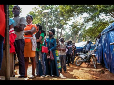 In this February 2022 photo, people queue to receive Pfizer coronavirus vaccinations at the Kiswa Health Centre III in the Bugolobi neighbourhood of Kampala, Uganda.