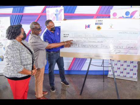 From left: Mona Sue Ho, senior manager of social development at the Jamaica Social Investment Fund (JSIF); Desmond McKenzie, minister of local government and rural development; and Omar Sweeney, managing director, JSIF, in dialogue as they look at a symbol