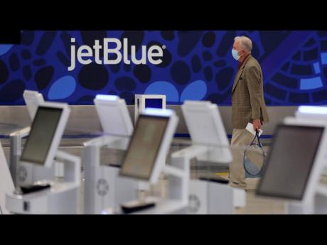 A traveller wearing a protective mask, due to the coronavirus outbreak, walks through the nearly empty JetBlue terminal at Logan Airport in Boston on May 29, 2020.