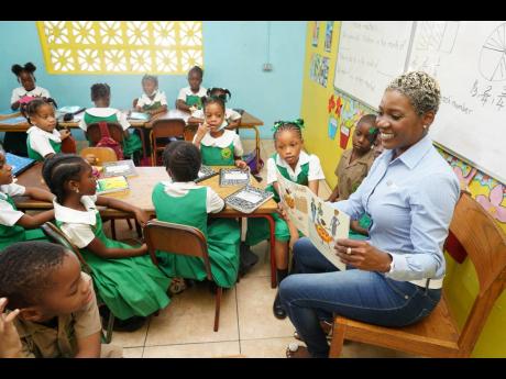 National Commercial Bank Head of Group Client Experience Sharon Williams reads to students of Mona Heights Primary, the adopted school assigned to the Matilda’s Corner branch.