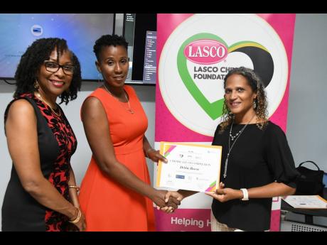 LASCO Corporate Communications Manager Danielle Cunningham (right) presents Debbie Bascoe, new graduate of the SWIFT E-Skills programme, with her Certificate of Completion during a graduation ceremony on April 19. LASCO Chin Foundation CEO Professor Rosale