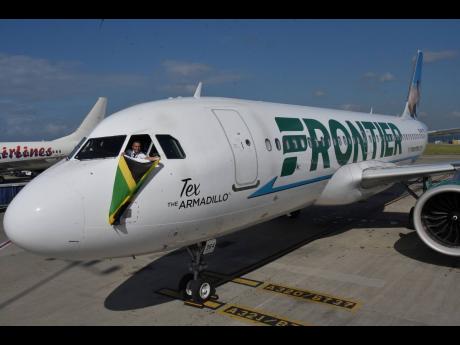 Credit: Ian Allen/Photographer Captain Jonathon Gauci waves a Jamaican flag as Frontier Airlines celebrated its inaugural flight on its Miami to Kingston route yesterday, landing at the Norman Manley International Airport with 75 passengers on board. The 45-minute flight, which originat