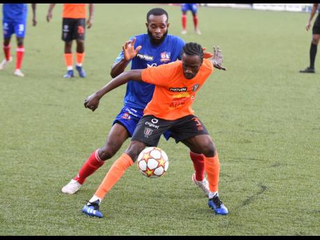 
Garden FC’s Davion Garrison holds off a tackle from Dunbeholdden FC’s Fabion Mcarthy during their Jamaica Premier League match back in February. Dunbeholden won the game 1-0.