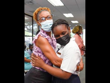 Ann-Marie Stanford hugs 11-year-old Dacia Lobban of Ocho Rios Primary after Stanford won first place in the Teachers Change the World Awards Ceremony hosted by ICWI on Monday.